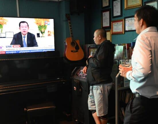 People watch as Cambodia's Prime Minister Hun Sen speaks during a special statement on television at a restaurant in Phnom Penh on July 26, 2023. - Cambodian Prime Minister Hun Sen, one of the world's longest-serving leaders, said on July 26, 2023 he will resign and hand power to his son, after almost four decades of hardline rule. (Photo by TANG CHHIN Sothy / AFP)