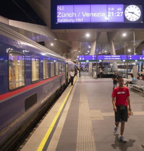 Passengers are seen on the platform in front of the Nightjet train line Vienna - Venice (-Zurich) of the Austrian Federal Railways (OeBB) as a sign shows the destinations and departure time at the main station in Vienna, Austria, on July 25, 2023. (Photo by Alex Halada / AFP)
