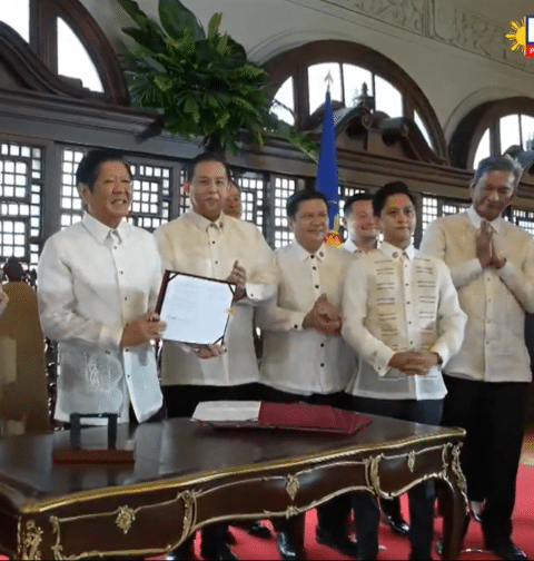 President Ferdinand Marcos Jr. presents a signed copy of the Maharlika Investment Fund Act (Republic Act 11954) at a ceremony in Malacanang on Tuesday, July 18, 2023. (Screengrab from RTVM video)
