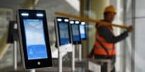 A construction worker walks past facial recognition screens at the entrance to the terminal building of the new Beijing Daxing International Airport, in Beijing on March 1, 2019. (Photo: Greg Baker/AFP)