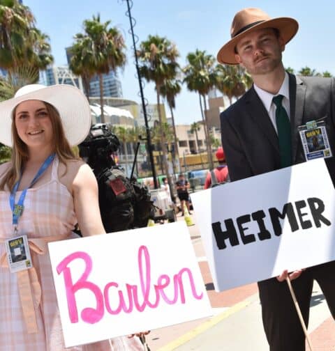 Cosplayers hold Barbenheimer signs outside the convention center during San Diego Comic-Con International in San Diego, California, on July 21, 2023. (Photo by Chris Delmas / AFP)