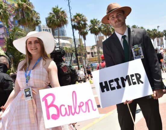 Cosplayers hold Barbenheimer signs outside the convention center during San Diego Comic-Con International in San Diego, California, on July 21, 2023. (Photo by Chris Delmas / AFP)