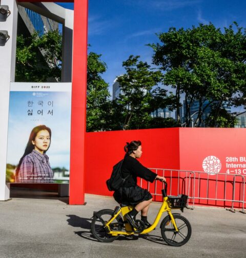A woman cycles past a poster of South Korean actress Go Ah-sung for the film 'Because I Hate Korea' at the Busan Cinema Center before the opening of the 28th Busan International Film Festival (BIFF) in Busan on October 4, 2023. (Photo by Anthony Wallace/ AFP)