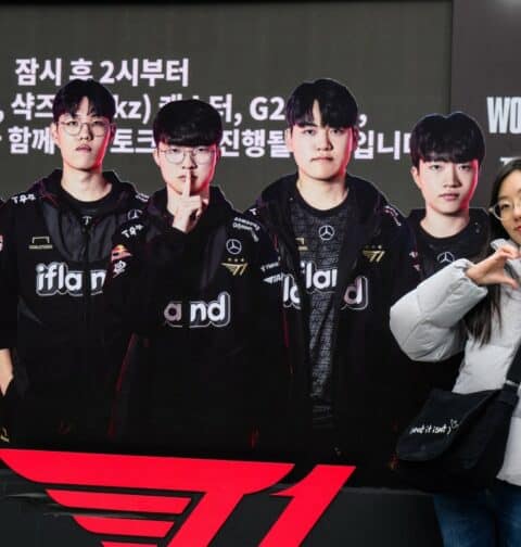 A woman poses next to a cardboard cutout of South Korea's T1 team at the '2023 Worlds Fan Fest' for the League of Legends World Championship 2023, also known as LoL Worlds 2023 or Worlds 2023, at Gwanghwamun Square in Seoul on November 17, 2023, ahead of the grand final on November 19. - The LoL season will culminate in a best of five match between South Korea's T1 and Chinese team Weibo Gaming at the sold 18,000-seat Gocheok Sky Dome in western Seoul on November 19. (Photo by Anthony WALLACE / AFP)