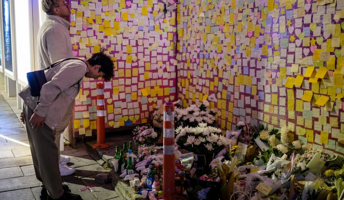 ystanders pay their respects in front of flowers and notes left on a wall in an alleyway in Seoul late October 28, 2023, which was the site of the October 29, 2022, tragic crowd crush that killed 159 people during Halloween celebrations, in Seouls popular Itaewon nightlife area. (Photo by ANTHONY WALLACE / AFP)