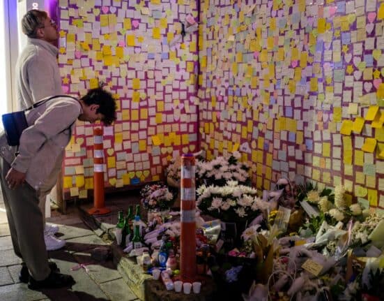 ystanders pay their respects in front of flowers and notes left on a wall in an alleyway in Seoul late October 28, 2023, which was the site of the October 29, 2022, tragic crowd crush that killed 159 people during Halloween celebrations, in Seouls popular Itaewon nightlife area. (Photo by ANTHONY WALLACE / AFP)