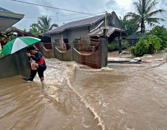 A man wades through floodwaters brought about by heavy rains at a residential neighbourhood in Propseridad town, Agusan del Sur province on southern Mindanao island on February 1, 2024. - Floods and landslides triggered by torrential rain have killed six people in the Philippines, with one other person missing, rescuers said February 1. (Photo by Erwin MASCARINAS / AFP)